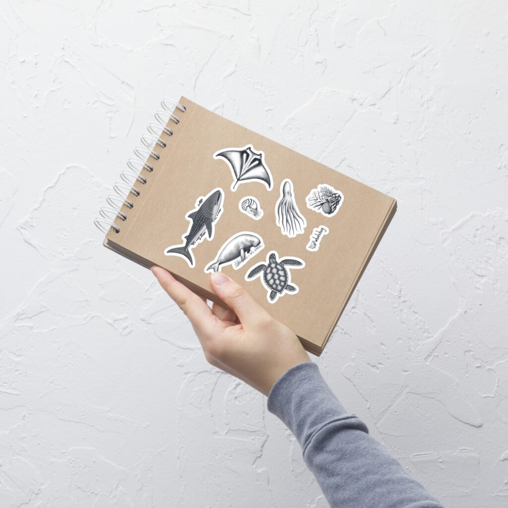 hand holding kraft notebook decorated with marine biology sticker sheet whalehug