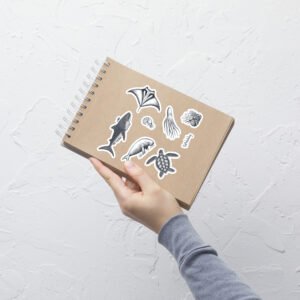 hand holding kraft notebook decorated with marine biology sticker sheet whalehug